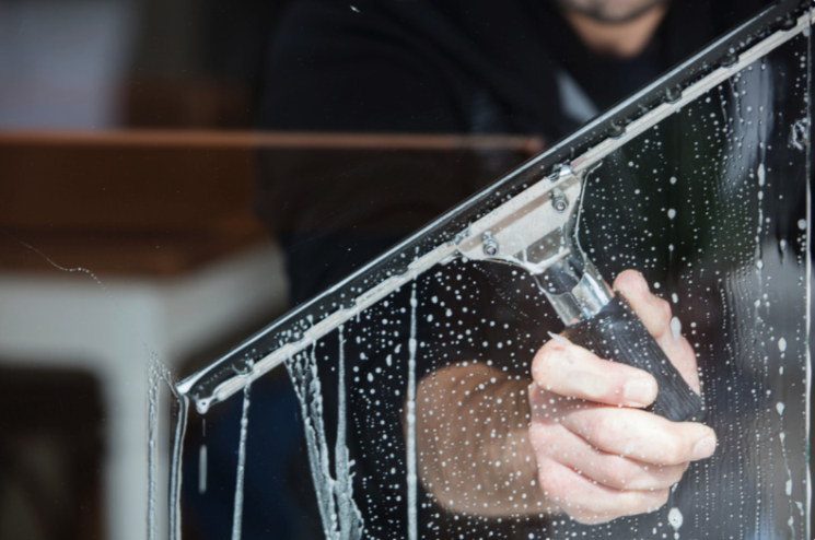 Window cleaner squeegeeing soapy glass